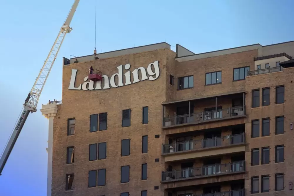 Exterior shot of the Landing building with a man on a crane beside the logo.