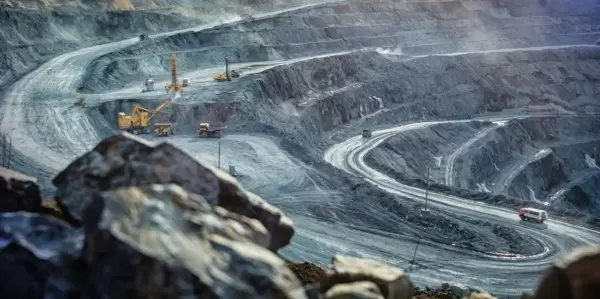 A tilt-shift photo of a massive mining operation on the side of a hill.