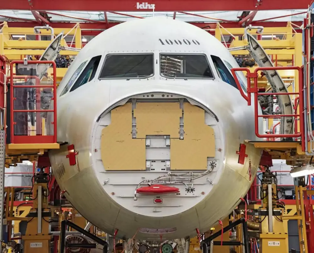 The front of an airplane with the nose cone removed being supported by yellow scaffolding.